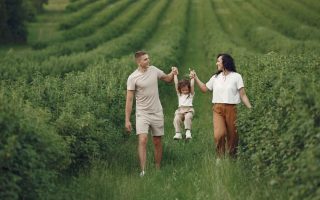 A happy family walking in a lush, green rural field together.