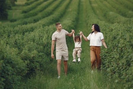 A happy family walking in a lush, green rural field together.